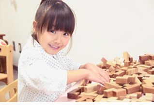 木の積み木で遊びながら学ぶ女の子